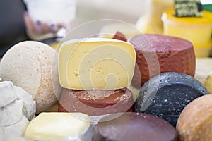 Cheese wheels different grades and cut pieces on market counter, colorful colors. Gastronomic dainty products on market