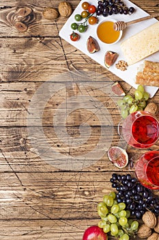 Cheese, wine, baguette grapes figs honey and snacks on the rustic wooden table top with copy space.