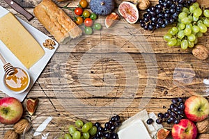 Cheese, wine, baguette grapes figs honey and snacks on the rustic wooden table top with copy space