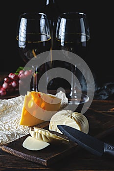 Cheese wine and bunches of grapes on a black background