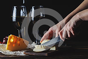 Cheese wine and bunches of grapes on a black background