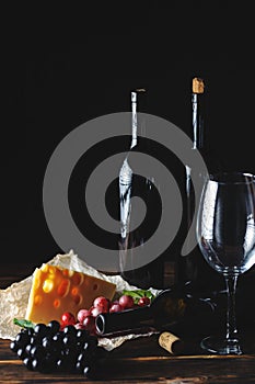 Cheese wine and bunches of grapes on a black background