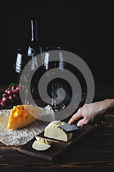 Cheese wine and bunches of grapes on a black background