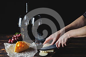 Cheese wine and bunches of grapes on a black background