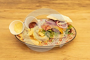 Cheeseburger, bacon, red onion, homemade fries, arugula, cheddar cheese, ketchup and mayonnaise on a colorful plate