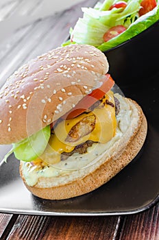 Cheeseburger with bacon and tartar sauce and garden salad