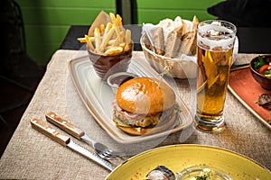 Cheeseburger with french fries and glass of beer on the table at restaurant