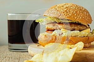 Cheeseburger on wooden plate and glass of cola