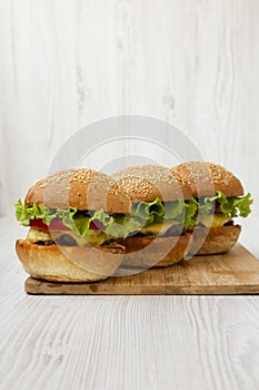 Cheeseburgers on bamboo board on white wooden background, side view