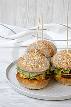 Cheeseburgers on grey plate over white wooden background, low angle view