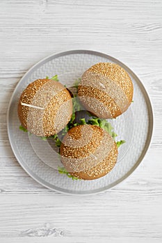 Cheeseburgers on grey plate over white wooden background, overhead view. Close-up