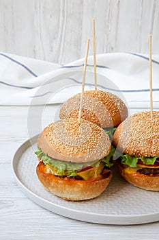 Cheeseburgers on grey plate on white wooden background, low angle view.