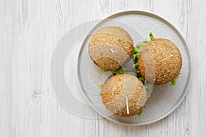 Cheeseburgers on grey plate on white wooden background, top view. Flat lay, overhead, from above.