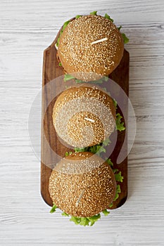 Cheeseburgers on wooden board over white wooden background, view from above. Closeup