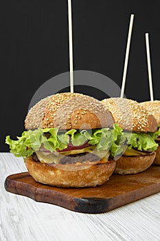 Cheeseburgers on wooden board, side view. Close-up