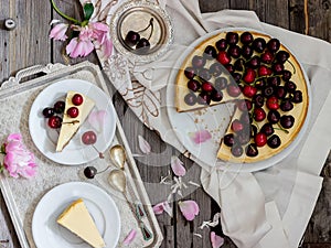 Cheesecake with cherry, two slices on saucers and metal tray on a wooden table. .