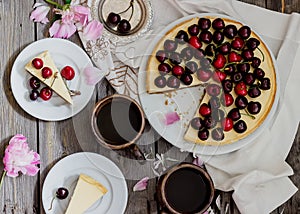 Cheesecake with cherry, two slices on saucers and metal tray on a wooden table. .