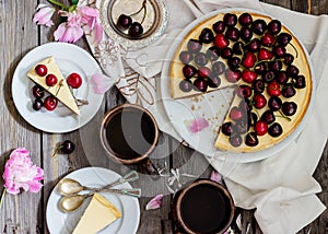 Cheesecake with cherry, two slices on saucers and metal tray on a wooden table. .