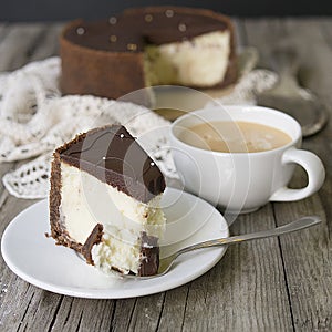 Cheesecake with chocolate and cup of coffee. Slice of classical New York cheesecake poured with chocolate sauce. Rustic