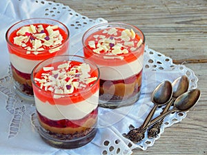 Cheesecake dessert in glass jar on wooden background.: chocolate biscuit, salted caramel, strawberry jelly, cheese mousse, chocola