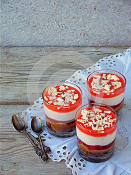 Cheesecake dessert in glass jar on wooden background.: chocolate biscuit, salted caramel, strawberry jelly, cheese mousse, chocola