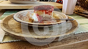 Cheesecake eating in progress. Ceramic plate on a wooden serving tray.