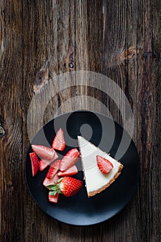 Cheesecake and fresh strawberries on black plate