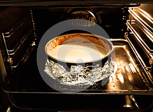 Cheesecake in the oven on water bath. Springform pan in foil. Baking process. Homemade desserts. Tasty pastry