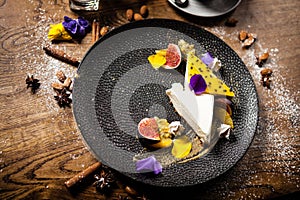 Cheesecake with passionfruit, fig and orange on a plate. Delicious healthy food closeup served for lunch on a table in