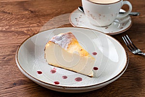 Cheesecake slice, New York style classical cheese cake on wooden background. Slice of tasty cake on white plate served