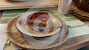 Cheesecake and spoon on the plate. Ceramic plate on a wooden serving tray.