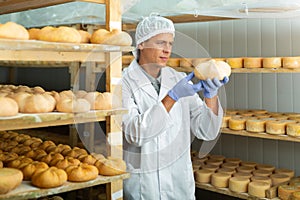 Cheesemaker checking aging process of cheese in maturing chamber