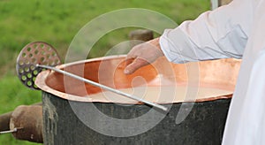 cheesemaker checks with hand the milk's temperature inside the c