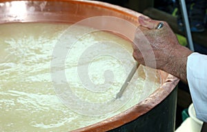 CHEESEMAKER mixes the milk in copper pot for chee