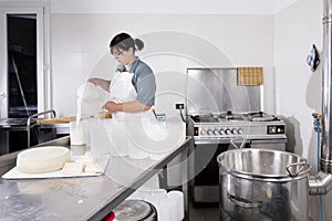 Cheesemaker pours the curdled milk into the plastic forms