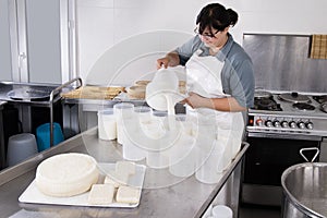 Cheesemaker pours the curdled milk into the plastic forms