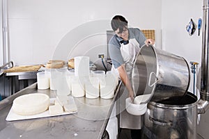 Cheesemaker pours the curdled milk into the plastic forms