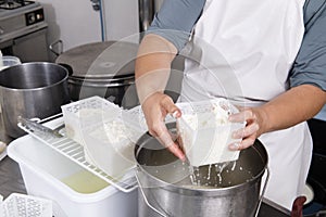 Cheesemaker pours the curdled milk into the plastic forms