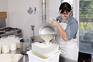 Cheesemaker pours the curdled milk into the plastic forms