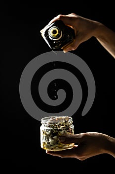 Cheesemaker showing the proceeding to make cheese , Chef hands adding olive oil in Jar with cheese marinated in oil on white