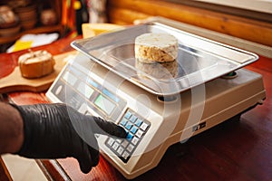 cheesemaker weighs cheese on scales, home production, business.