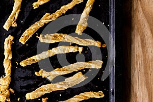 Cheesy cheese pastry straws with sesame seeds and bits of chili in oven pan  - top view photo