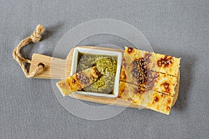 Cheesy keto sticks with sesame and pesto sauce on wooden background