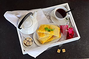 Cheesy pancakes with tea on a wooden tray.
