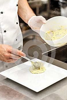 Chef add mashed potatoes on plate