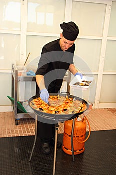 Chef adding the final touch to paella, the shells