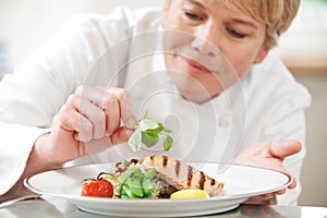 Chef Adding Garnish To Meal In Restaurant Kitchen
