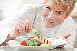 Chef Adding Garnish To Meal In Restaurant Kitchen
