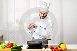 Chef Adding Pepper In Frying Pan Seasoning Dish In Kitchen