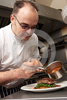 Chef Adding Sauce To Dish In Restaurant